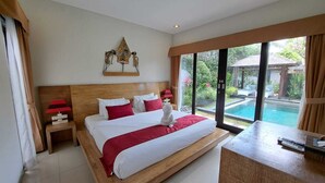 A spacious bedroom with a large bed, a wooden headboard, a nightstand with a lamp, and a view of a swimming pool through large windows. - Agata Villas (Seminyak)