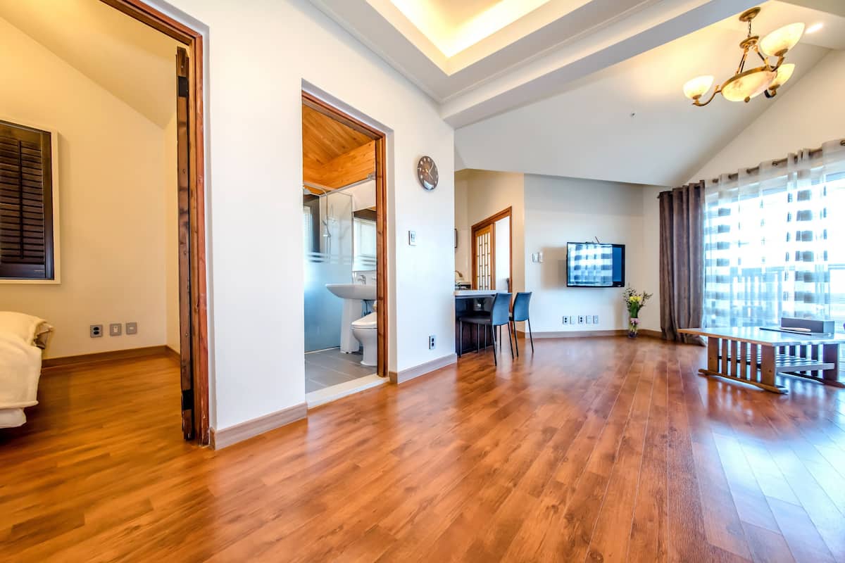 A spacious living room with hardwood flooring, a dining area, and a view of the city through large windows.