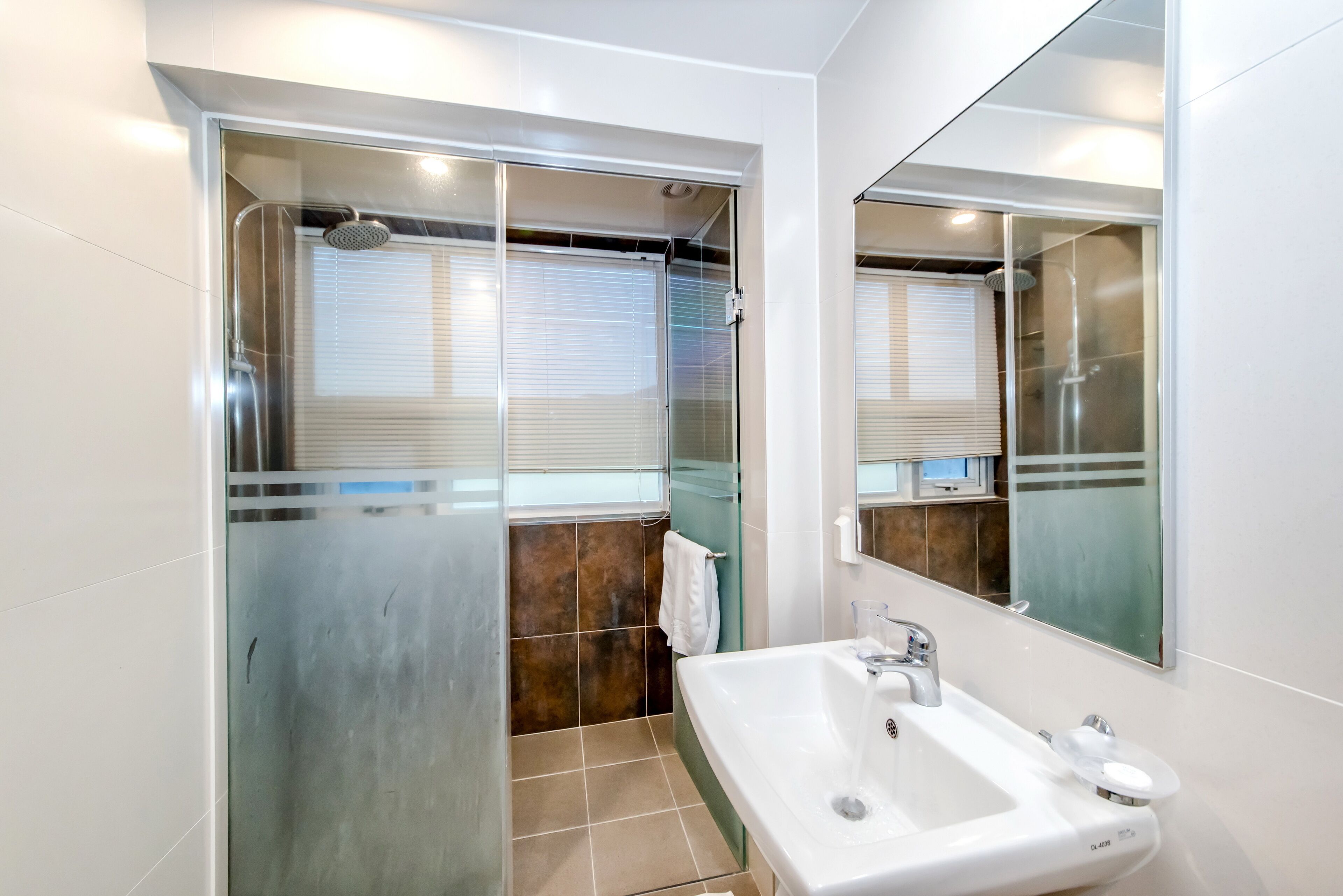 Une salle de bain moderne avec une douche à parois de verre, un lavabo blanc et un miroir.