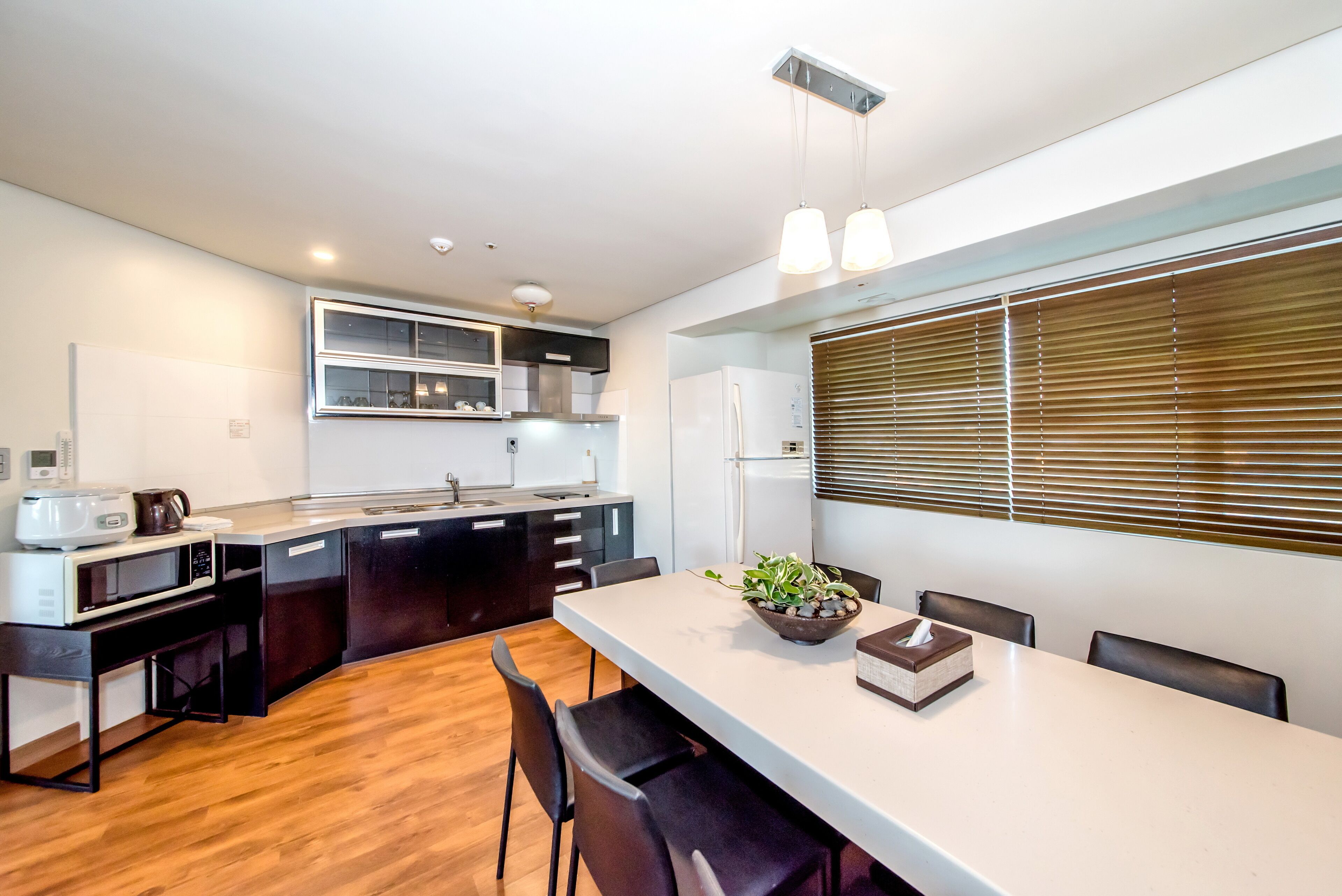 A modern kitchen with a central island, built-in appliances, and a dining area with a long table and chairs.