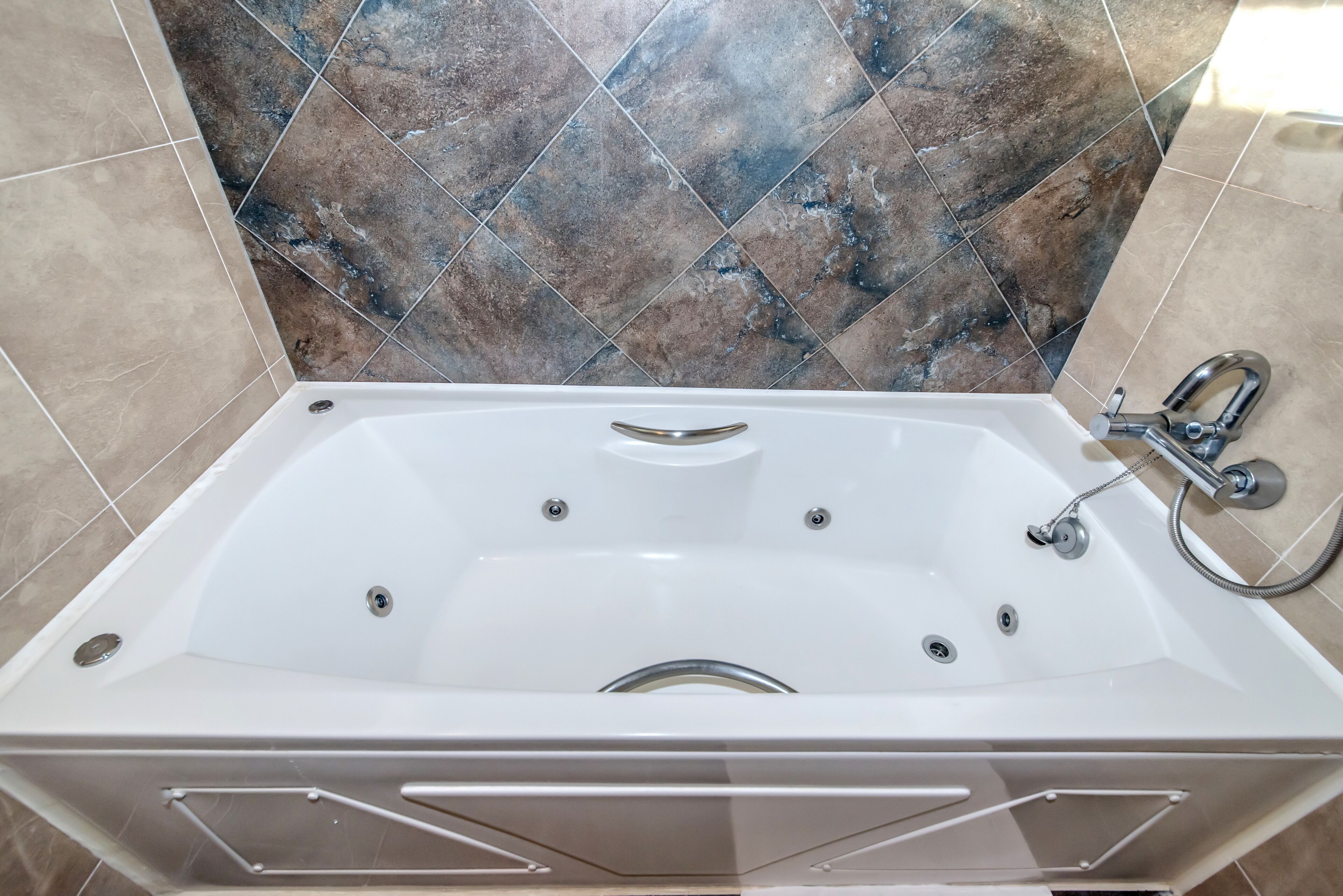 Un baño moderno con una bañera independiente, zona de ducha y pared revestida de azulejos.