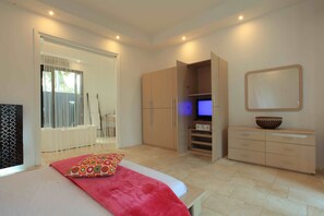 A bedroom with a bed, a TV, a wardrobe, and a mirror. - Verve Villa Senggigi (Batukliang)
