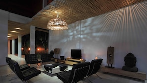 Ein modernes Wohnzimmer mit schwarzen Ledersofas, einem Holztisch und einem Fernseher auf einem Holzboden.
