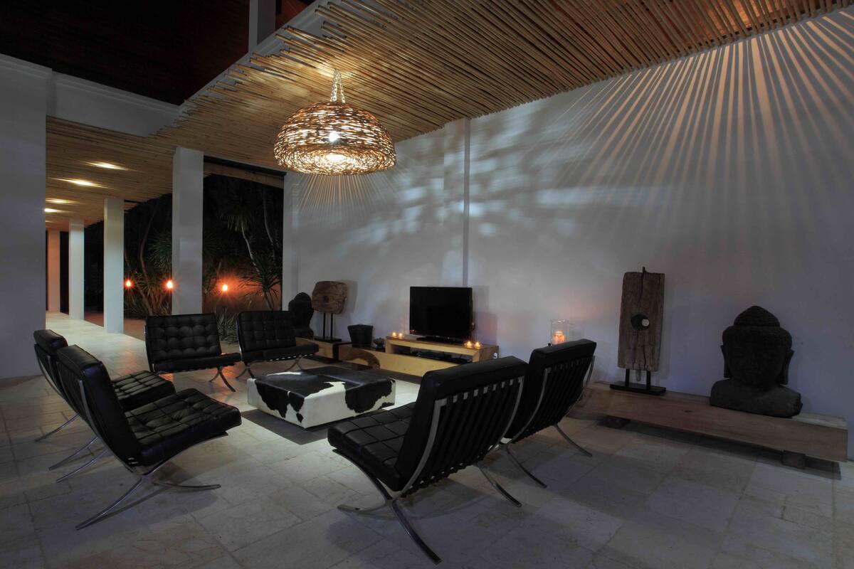 Una sala de estar moderna con sofás de cuero negro, una mesa de centro de madera y un televisor sobre un mueble de madera.