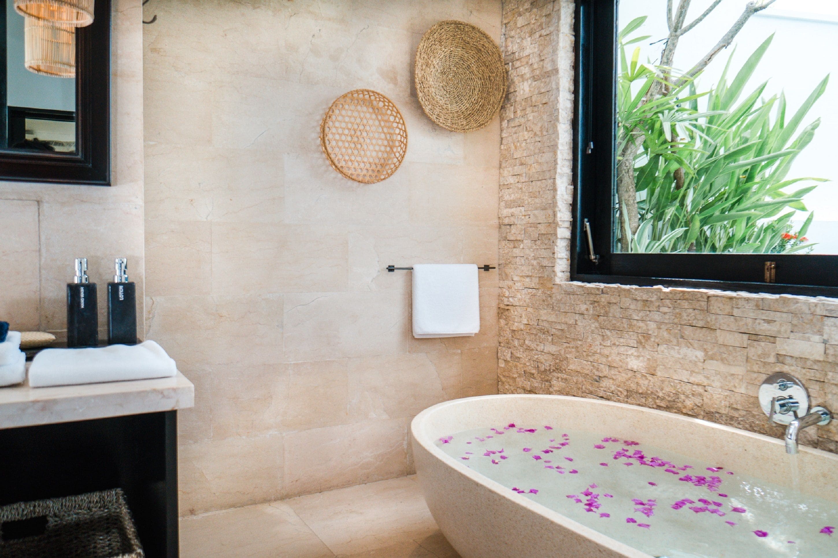 A bathroom with a bathtub, a towel rack, and a window with plants.