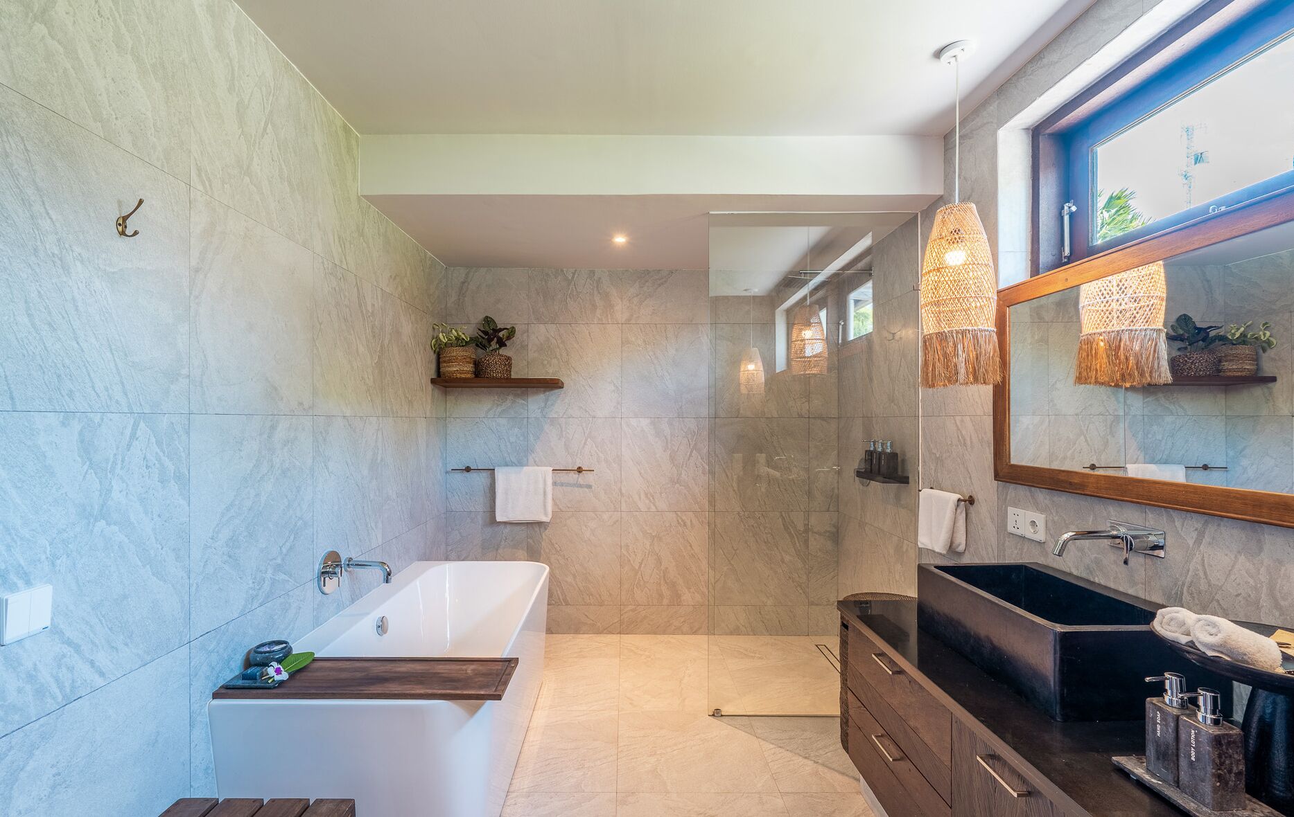 A modern bathroom with a freestanding bathtub, a vanity with a dark countertop, and a large mirror.