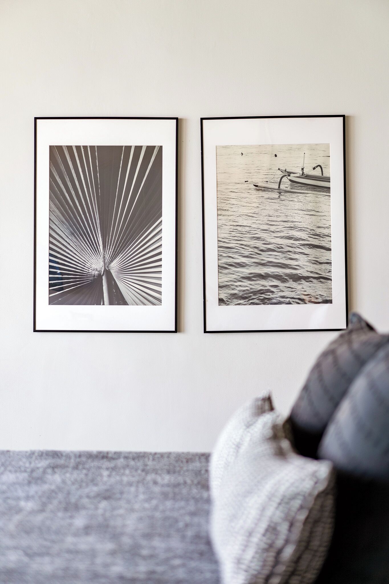 Dos fotografías en blanco y negro, enmarcadas en una pared, una con un diseño de rayos de sol y la otra mostrando un barco en el agua.