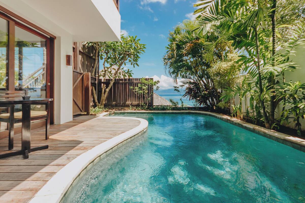 A swimming pool with a wooden deck and a view of the ocean.