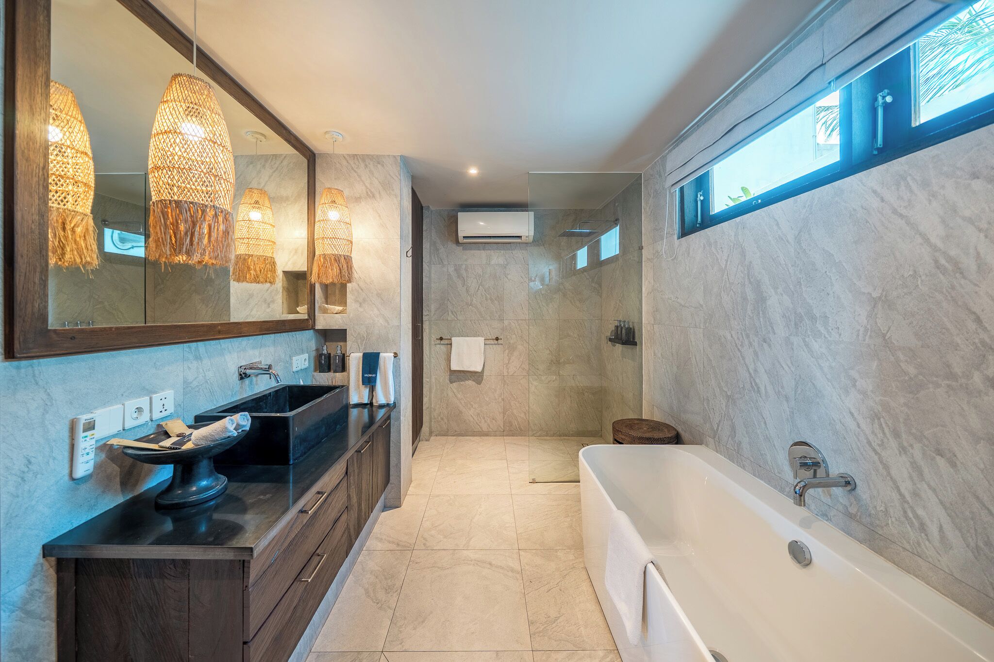 A modern bathroom with a large mirror, a bathtub, a sink with a black countertop, and a shower area.