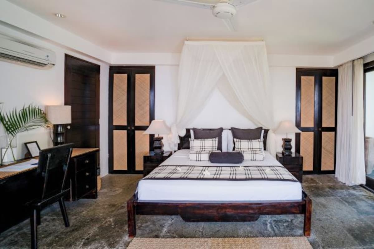 Un dormitorio con cama, mesitas de noche, escritorio y silla.