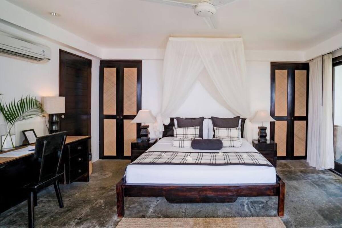 A bedroom with a bed, bedside tables, a desk, and a chair.