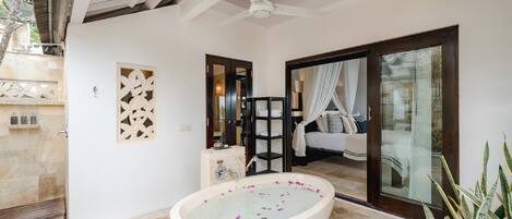 A bathroom with a freestanding bathtub, a ceiling fan, and a large glass door leading to a balcony.