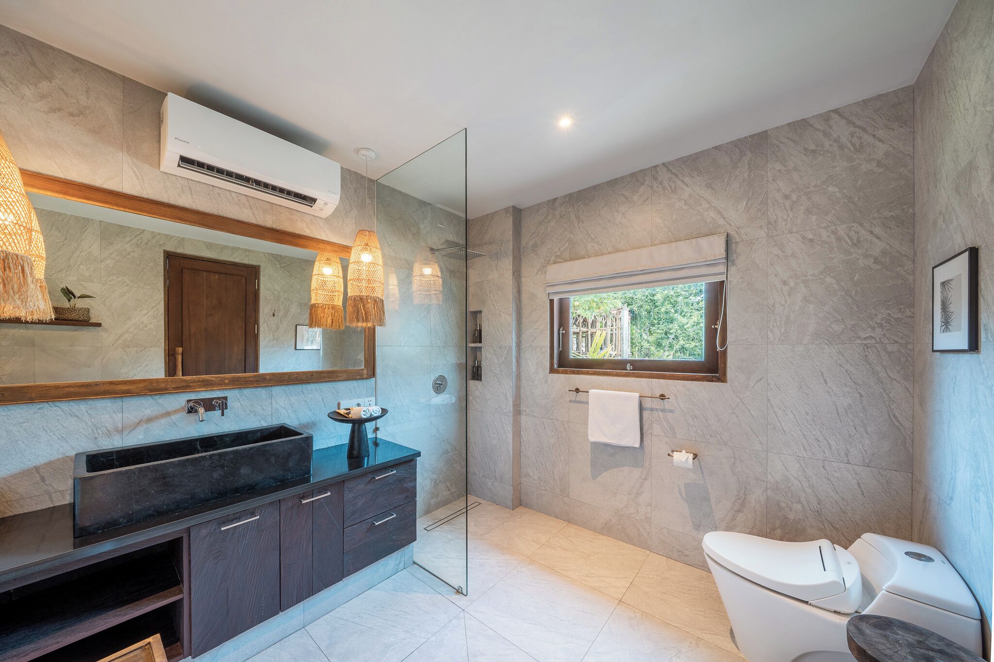 Un bagno moderno con un grande specchio, un mobile lavabo in legno scuro e una cabina doccia in vetro.