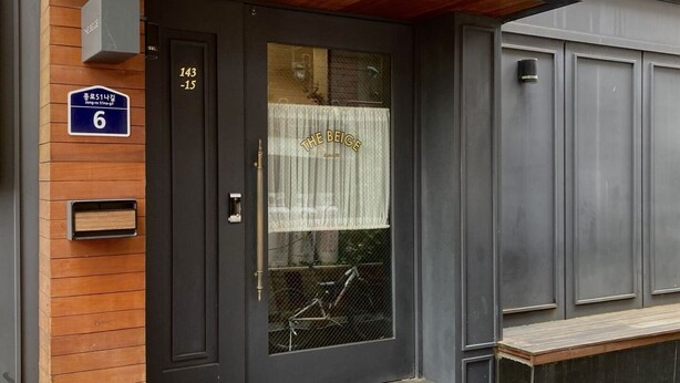 A black door with a window, a sign reading "THE BEIGE," and a sign with the number "6." - Hostel Beige 2nd (Seoul)