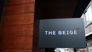 A sign for "The Beige" with a modern building facade in the background. - Hostel Beige 2nd (Seoul)