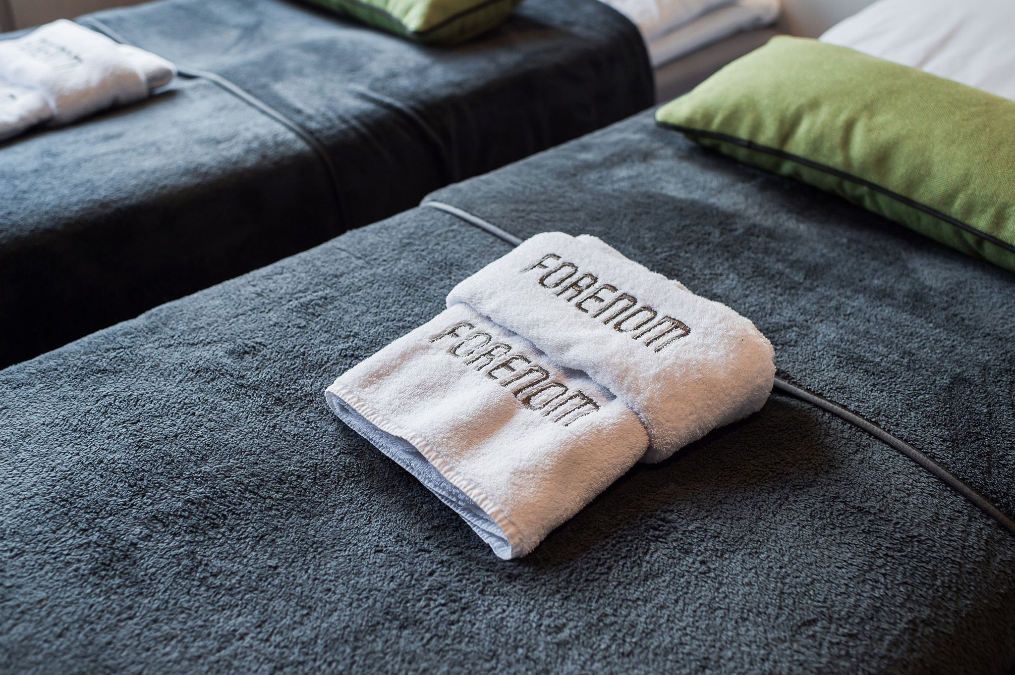 A neatly made bed with a folded towel on it.