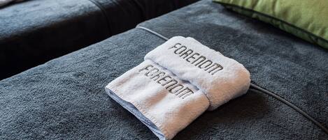 A neatly made bed with a folded towel on it.