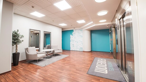 Eine moderne Hotelhalle mit Holzboden, einer Rezeption, einer Sitzecke und einer großen Karte an der Wand.