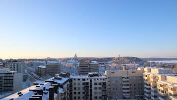 A high-rise building complex with multiple floors and balconies, surrounded by other buildings and a snowy landscape.