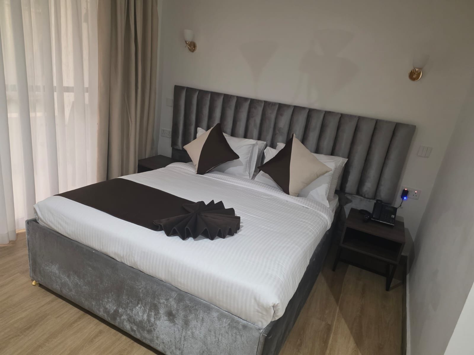 A hotel room with a large bed, a bedside table with a lamp, and a power outlet.