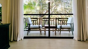 A room with a sliding glass door leading to a balcony with two chairs and a table. - Park Place Hotel (Nairobi)