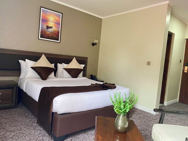 Habitación de hotel con cama, mesita de noche, lámpara y un cuadro en la pared.