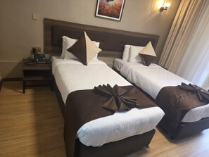 Ein Hotelzimmer mit zwei Betten, einem Nachttisch mit Telefon und einem Bild an der Wand.