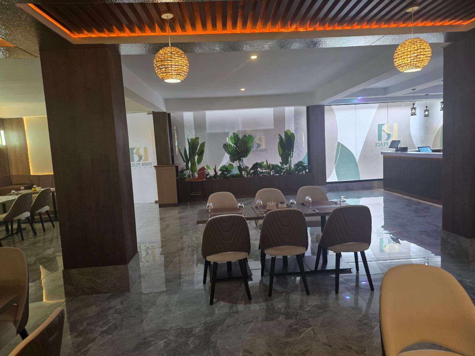 A modern hotel lobby with a reception desk, seating area, and a large window.