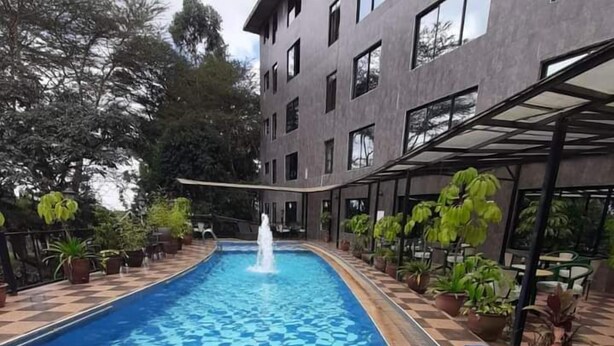 A swimming pool with a checkered pattern, surrounded by potted plants and a building with multiple windows. - Park Place Hotel (Nairobi)