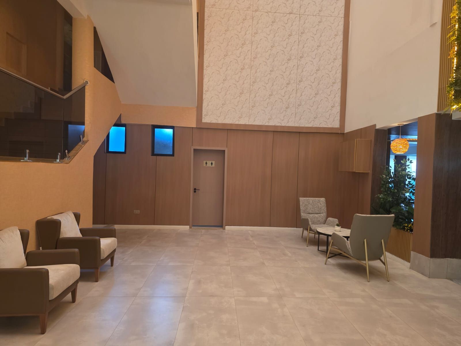 A spacious lobby with a high ceiling, a staircase, and a seating area with sofas and chairs.