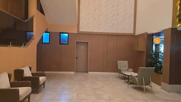 A spacious lobby with a high ceiling, a staircase, and a seating area with sofas and chairs.