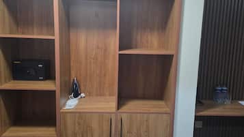Un armario de madera con varios compartimentos, una pequeña repisa con un dispositivo negro y una mascarilla en la repisa inferior.