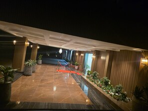 Eine Hotelhalle mit Marmorboden, Blumentöpfen und einem roten Teppich zum Eingang.