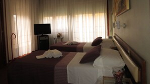 A hotel room with two beds, a TV, a small table with a vase, and a painting on the wall. - Hotel San Michele (Aprilia)