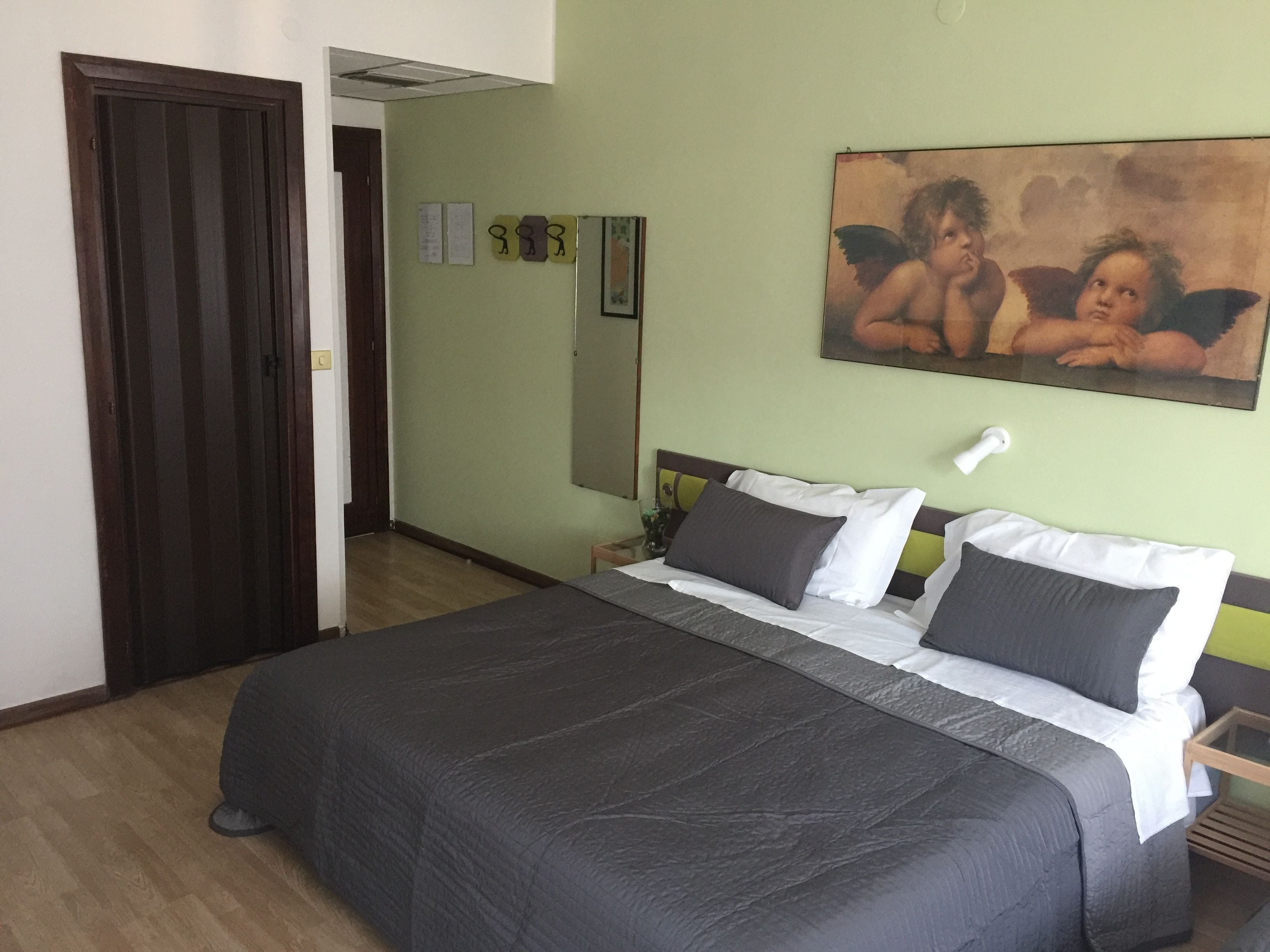 Ein Schlafzimmer mit einem großen Bett, einer Holztür, einer grünen Wand und einem Gemälde von Cherubs.