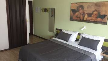 Ein Schlafzimmer mit einem großen Bett, einer Holztür, einer grünen Wand und einem Gemälde von Cherubs.
