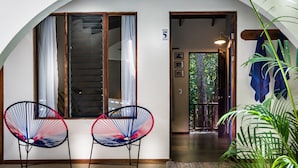 Una habitación con dos sillas, una puerta con un número y vistas al exterior.