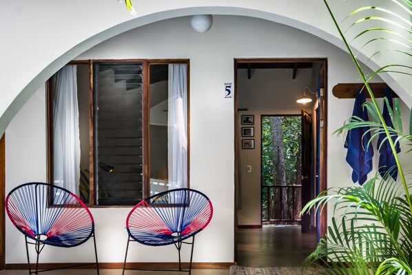 A room with two chairs, a door with a number, and a view of the outdoors.