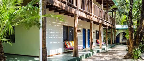 A resort with a covered outdoor area, wooden deck, and palm trees.