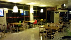 A restaurant with multiple tables and chairs, a TV screen, and a sign indicating it is a hotel.