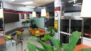 Habitación de hotel con kitchenette, zona de comedor con sillas coloridas, ventana grande con vistas y puerta con un cartel.