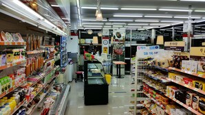 Un pasillo de supermercado con diversos productos envasados y un mostrador refrigerado.