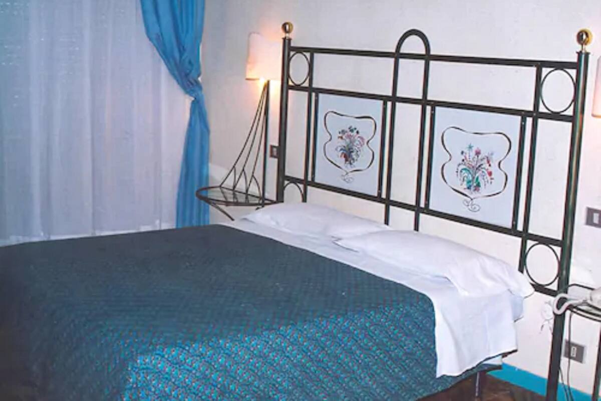 A bed with a metal frame, a white pillow, and a blue bedspread.
