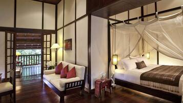 A bedroom with a bed, bedside table, and a view of a balcony.
