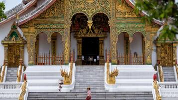 A temple with ornate golden decorations, a central statue, and a staircase leading to the entrance.