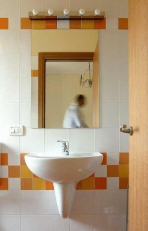 A bathroom with a white sink, a mirror, and a door.