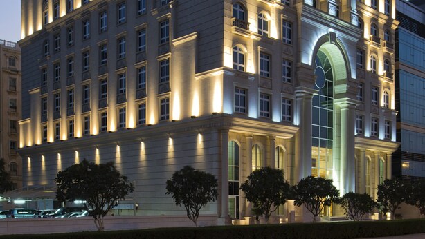 Un hotel grande de varios pisos con estilo arquitectónico clásico, que cuenta con una entrada destacada con un arco grande y múltiples ventanas en cada planta.