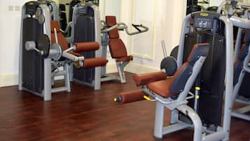 A gym with exercise machines and wooden flooring.