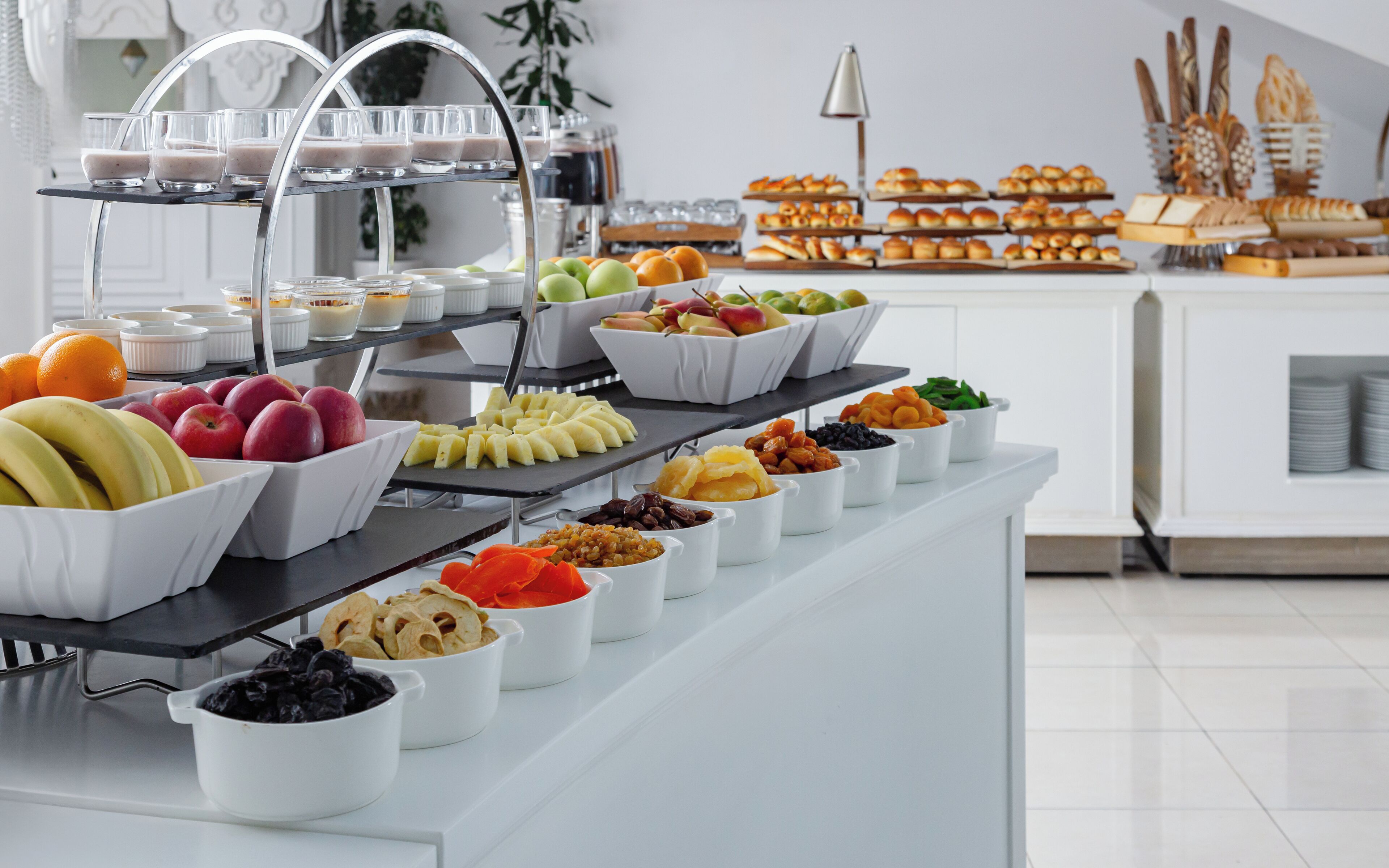 Un bufé con diversas frutas, nueces y pastelería.