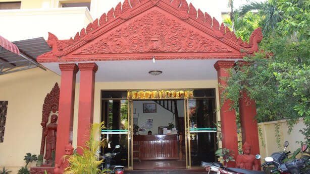 Un bâtiment doté d’un toit rouge traditionnel et d’un espace d’accueil.